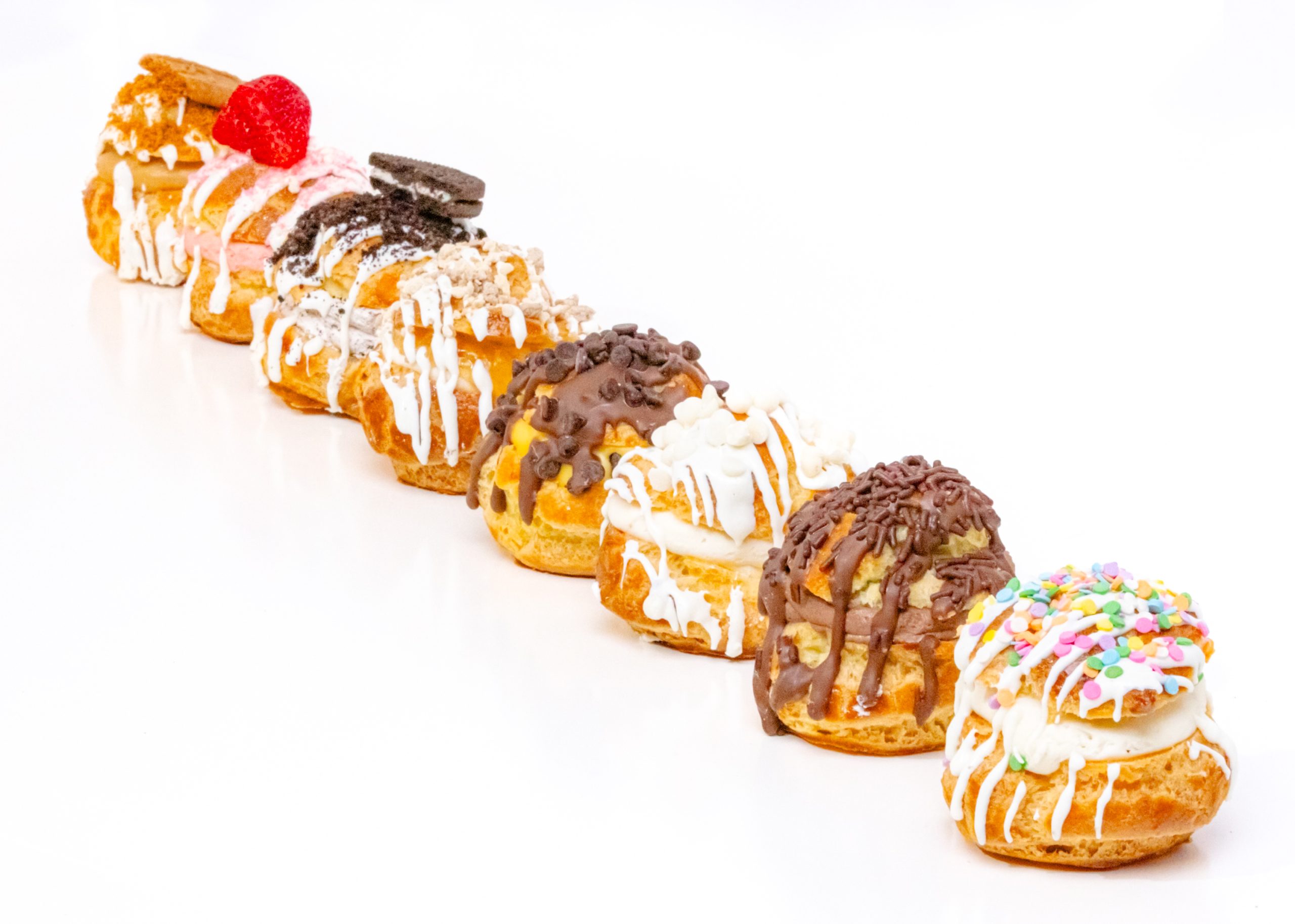 Cream puff filled with white ricotta cream, topped with apple cinnamon filling, white chocolate drizzle, and apple cake crumbs